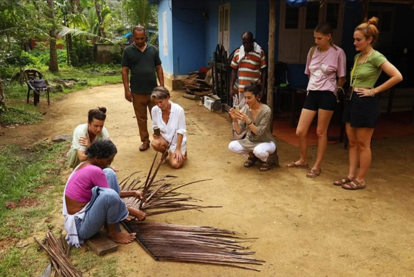 Travellers watching a palm-leaf craft demonstration