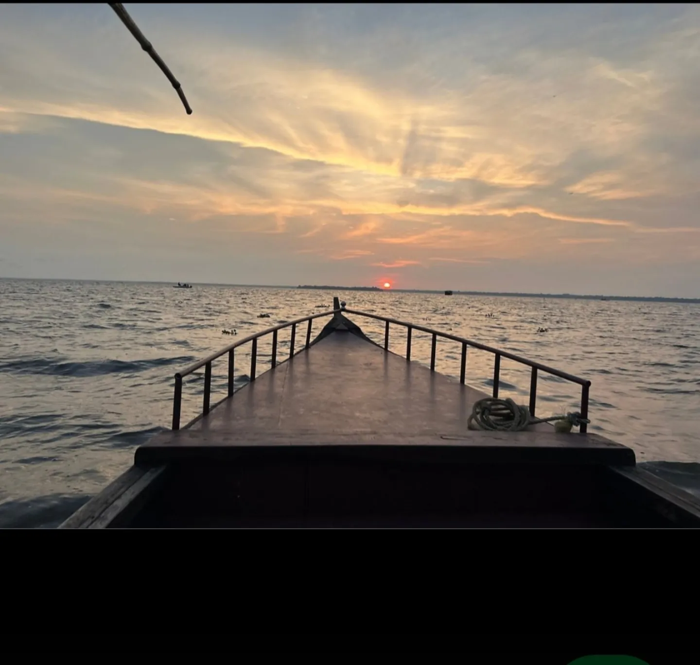 Sunset over the water, viewed from the bow of a boat