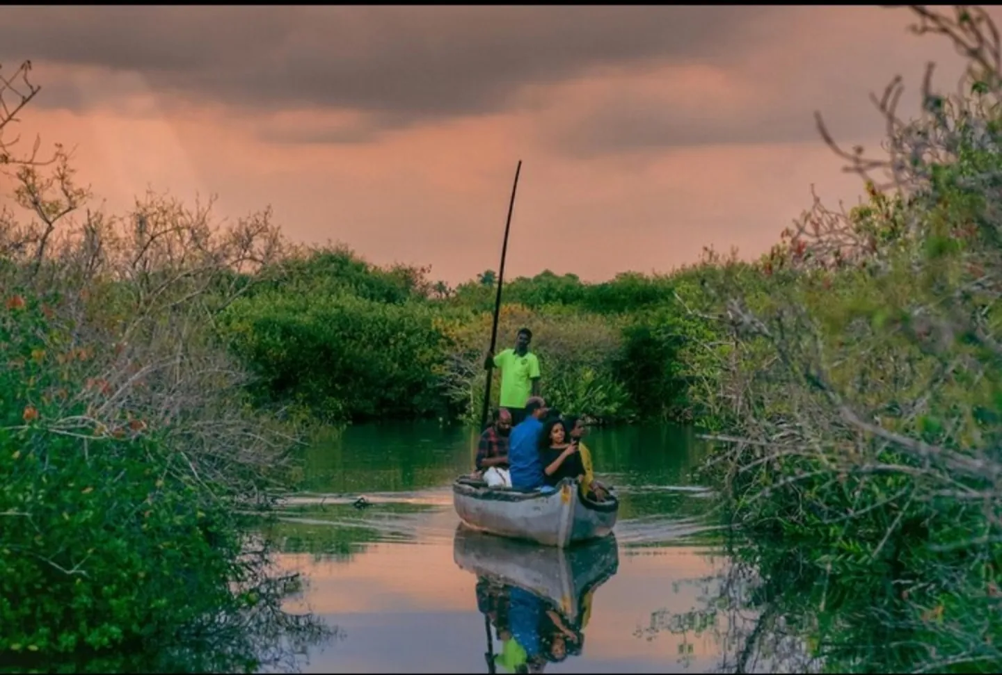 A canoe travelling along a quiet waterway at sunset