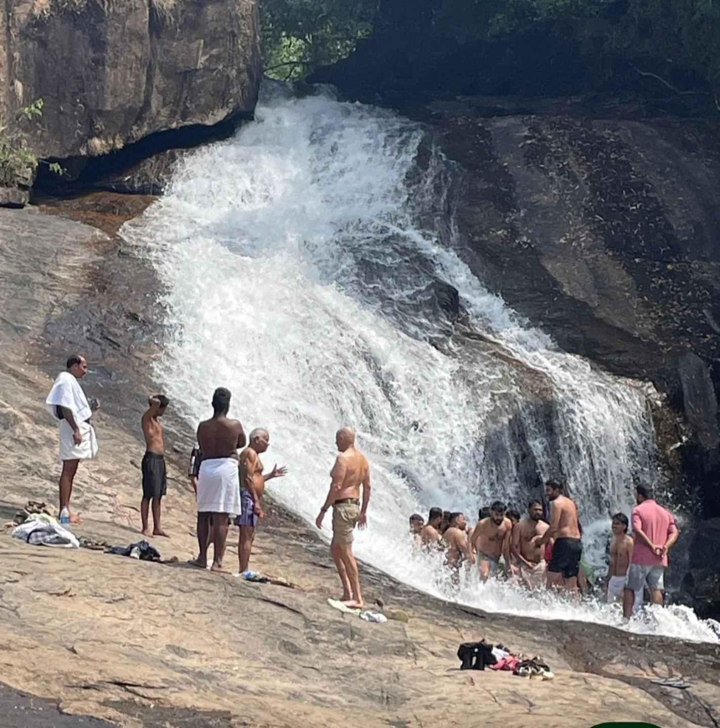 Visitors beside a waterfall in the Munnar region