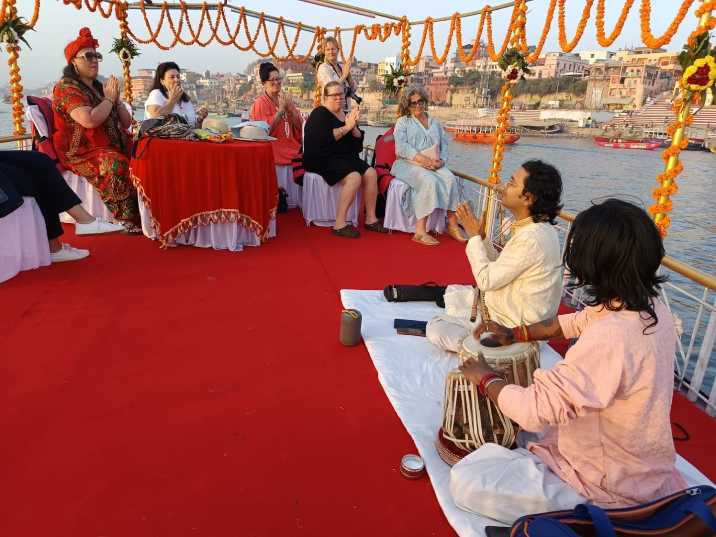 Travellers listening to musicians aboard a boat in Varanasi