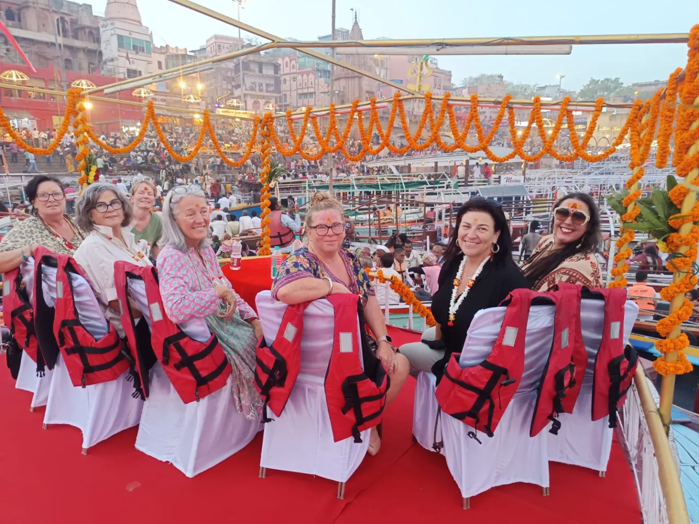 Travellers wearing life jackets aboard a decorated boat in Varanasi